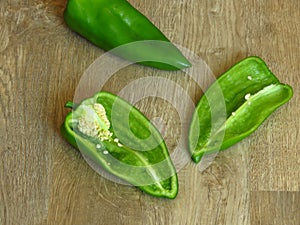 Long sweet green pepper cut in half on rustic style wood background. Pepper seeds.