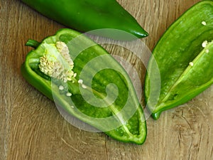 Long sweet green pepper cut in half on rustic style wood background. Pepper seeds.