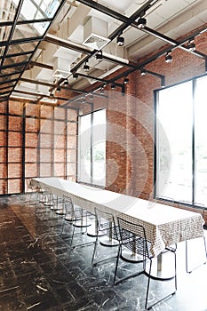 Long table with black steel chairs inside brick wall room decorated in loft style