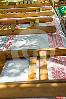 Long table covered with boho style cloth. Folding wooden chairs. Preparation for outdoor summer spring picnic or public fest.