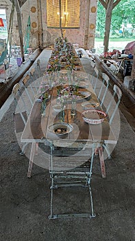 long table set in shabby chic style with plates, flowers and chairs