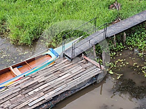 Long tail boat is floating near the wooden pontoon