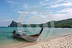 Long tail boat at Pi Pi island beach with blue sea mountain and