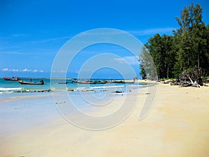 Long tail boats in a bay against blue sky at Nai Yang beach near the airport of Phuket, Thailand