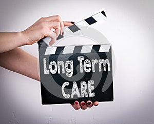 Long term care concept. Female hands holding movie clapper