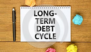 Long-term debt cycle symbol. Concept words Long-term debt cycle on beautiful white note. Beautiful wooden table background.