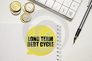 LONG TERM DEBT CYCLE on yellow sticker on pen with coin