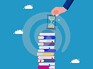 long term learning. Businessman hand holding hourglass on stack of books