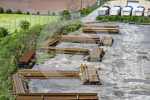 Long and thick, rust-covered steel bars stacked outside on a gravel square, viewed from above.