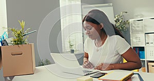 Long-time employee of company's marketing department sits in new office, got a promotion, talks via laptop to a