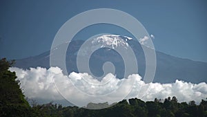 Long time lapse of white clouds move below majestic Kilimanjaro snowy mountain