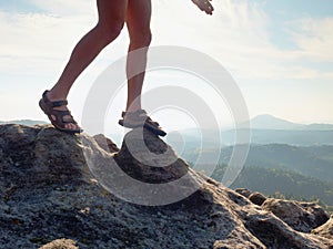 Long tired naked legs in hiking sandals on peak. Hiking in sandstone rocks, hilly landscape