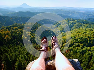 Long tired naked legs in hiking sandals on peak. Hiking in sandstone rocks, hilly landscape