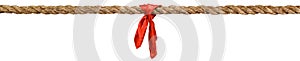 Long tug of war rope pulled tight, with red ribbon tie. Concept of conflict, competition, or rivalry.