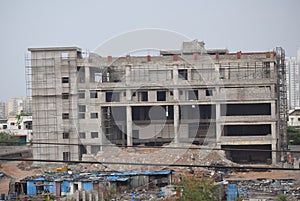 Long view of a incomplete concrete building nearby slum area