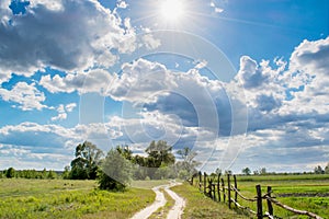 Long village way near the fields during sunny day