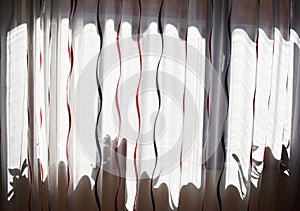 Long white curtain with black and red wavy strips and shadows