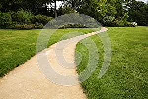 Long white curved garden path surrounded by lush foliage