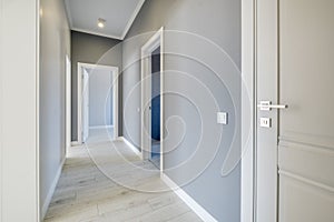 Long white empty corridor in interior of entrance hall of modern apartments, office or clinic