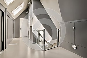 a long white hallway with stairs and a metal railing