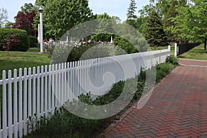 The long white picket fence is by the path.