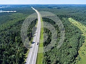 Long and wide highway going to horizon, freight semitrailer drives on lane, aerial view