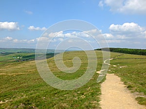 A long winding footpath running into the distance in stoodley moor in yorkshire with fields and farms in the distance