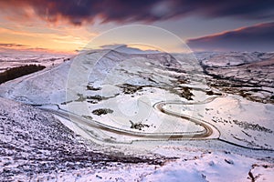 Long And Winding Road Leading Through Snow Covered Countryside at Sunset. Peak District, UK.