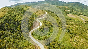 A long and winding road passing through green hills. Busuanga island. Coron. Aerial view. Philippines.