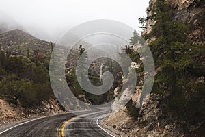 Long and winding road snaking through the fog-covered mountainside