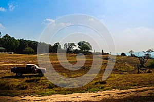 Long and winding rural road crosses the hills in the summer farm field with blue sky background and copy space for text.