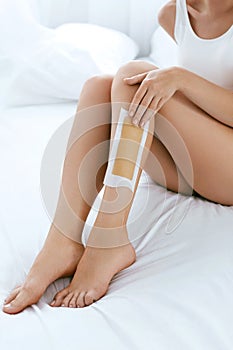 Long Woman Legs With Hair Wax Strip Closeup. Hair Removal