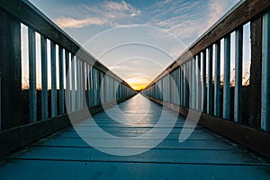 A long wooden boadwalk seems to stretch to infinity. Walkway leading to the sky at sunset, concept, copy space photo