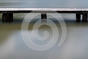 Long wooden boardwalk on a calm and placid mountain lake abstract view with copy space