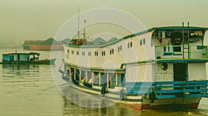 Long wooden boat loaded by passengers and goods cruising Mahakam River, East Borneo.