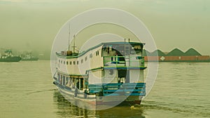 Long wooden boat loaded by passengers and goods cruising Mahakam River, East Borneo.