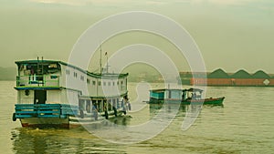 Long wooden boat loaded by passengers and goods cruising Mahakam River, East Borneo.