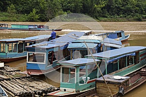 Long wooden boat taxis in Laos in a river pier