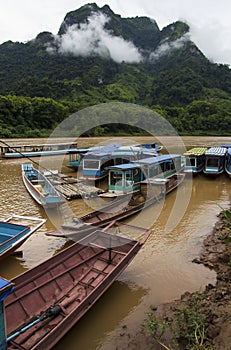 Long wooden boat taxis in Laos in a river pier