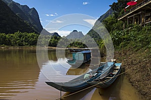 Long wooden boat taxis in Laos in a river pier