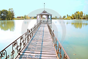 A long wooden bridge on the lake.There is a gazebo at the end of the bridge.