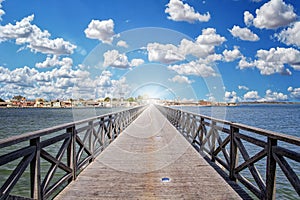 Long wooden bridge leading over a sea lagoon. It leads to Fadiouth Island in Senegal, Africa. Sun rays shine from the