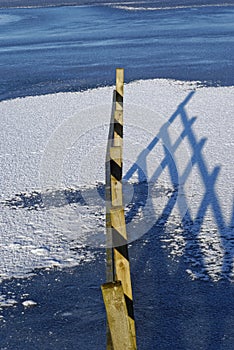 Long Wooden fence shadows being cast by the Winters sun at Murton Lochs in winter.