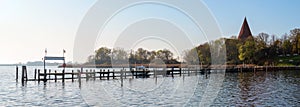 Long wooden jetty in the yacht port at the church in a bay on the island Poel near Wismar in the Baltic Sea, Germany, blue sky