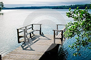 Long wooden pier and beautiful lake Saimaa, Finland on warm and windless summer day.