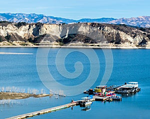 Long wooden pier and boats at California`s Lake Cachuma with San Rafael Mountains