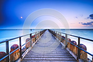 Long wooden pier extends over water toward the horizon. A leading line to the horizone