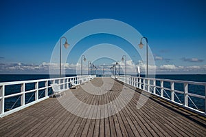 Long wooden pier with lanterns and white barriers