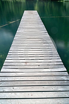 Long wooden pier leads out into a mountain lake in Arosa