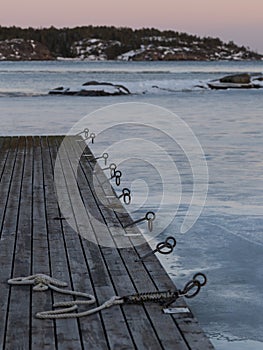 a long wooden pier sitting next to a frozen lake at dusk